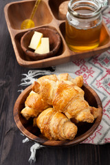 Croissants, honey and butter on a wooden background