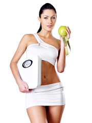 Healthy woman stands with the scales and green apple.