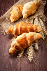 Croissants with spikelets of wheat on the wooden background