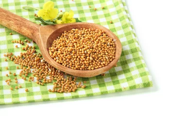 Poster Mustard seeds in wooden spoon with mustard flower isolated © Africa Studio