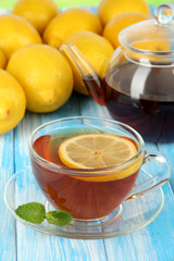 Cup of tea with lemon on table on blue background