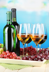 Wine bottles and glasses of wine on tray, on bright background