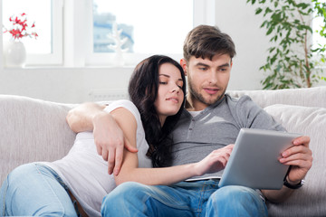 couple sitting on a couch with tablet computers