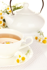 Cup of herbal tea with camomiles close up