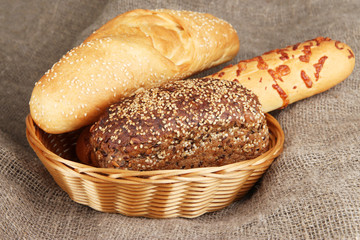 Baked bread in wicker basket on burlap background