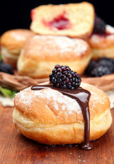 Tasty donuts with chocolate and berries on wooden table