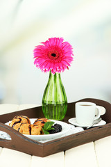 Wooden tray with breakfast, on wooden table, on light