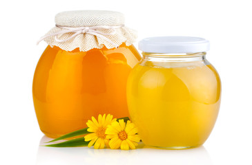 Sweet honey in glass jars with flowers isolated on white