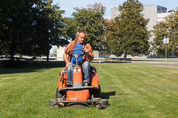 man driving a red lawn mower (tractor)