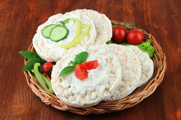 Tasty crispbreads with vegetables on wooden background