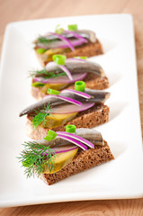 Sandwiches of rye bread with herring, onions and herbs.
