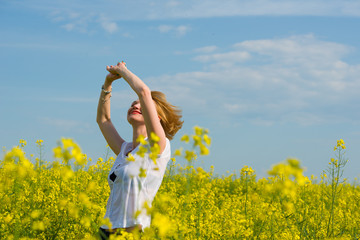 Young woman standing in yellow rapeseed field