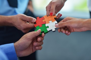 Group of business people assembling jigsaw puzzle - obrazy, fototapety, plakaty