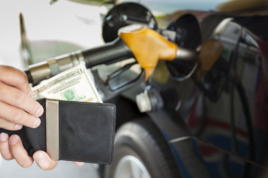 man counting money with gasoline refueling car at fuel station