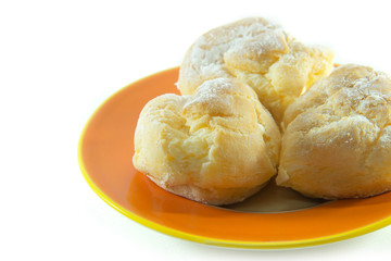 Three cream puffs on orange plate closeup