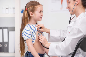 Medical exam. Cheerful young doctor in lab coat examining little