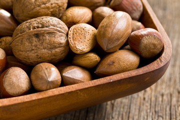 various unpeeled nuts in wooden bowl