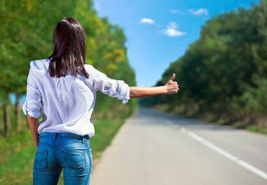 Woman hitchhiking back view