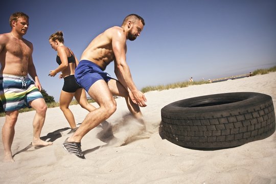 Tire flip crossfit exercise on beach
