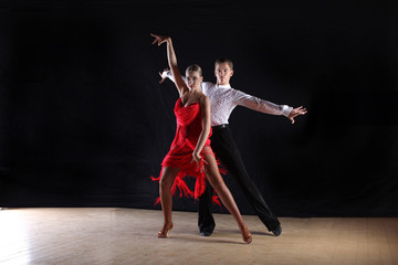 Latino dancers in ballroom against black background