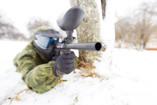 paintball player with marker at winter outdoors