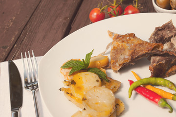 Lamb and roasted potatoes on wooden table