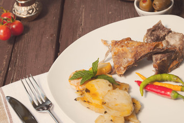 Lamb and roasted potatoes on wooden table
