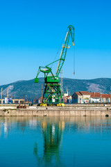 Large industrial crane in the river port with blue sky above.