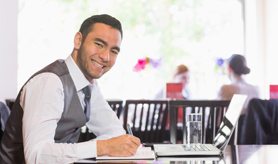 Fototapeta na wymiar Smiling businessman writing while looking at camera