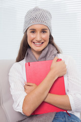 Cheerful brunette with winter hat on holding folder