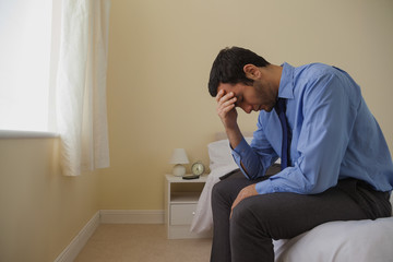 Fototapeta premium Mournful man sitting head in hands on his bed