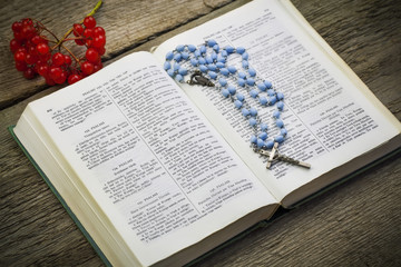 Bible with rosary on old boards