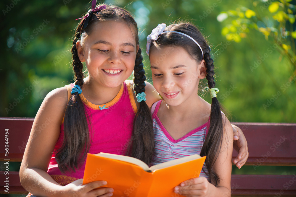 Wall mural sisters reading book in summer park