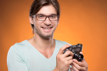 Man with camera. Cheerful young man holding camera in his hands