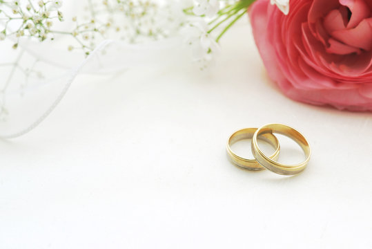 Wedding rings on silk with flowers and copy space