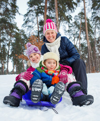 Fototapeta na wymiar Funny family is sledging in winter-landscape