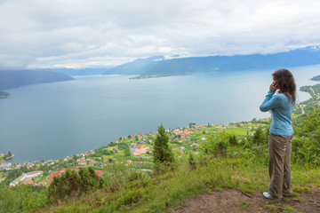 Naklejka premium Woman talking on mobile phone at the edge of cliff