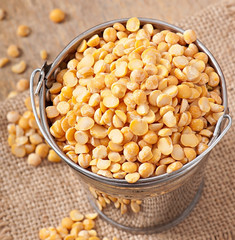 Dry peas in bucket on wooden background