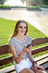 Young beautiful woman honding mobile phone in hand and sitting