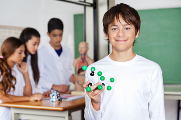 Teenage Schoolboy Holding Molecular Structure In Biology Class