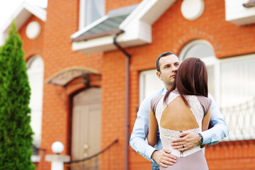 Happy couple standing in front of new home