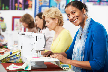 Group Of Women Using Electric Sewing Machines In class