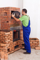 Worker in uniform building a traditional mass stove