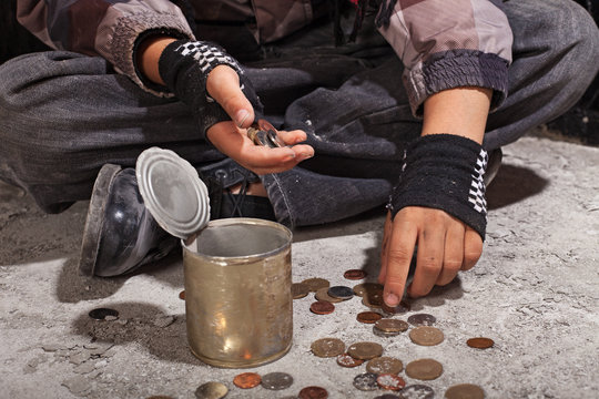 Beggar child counting coins sitting on damaged concrete floor
