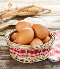 Eggs in a wicker basket on vintage planked wood table