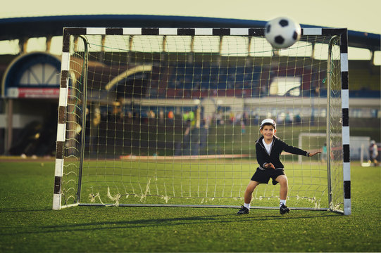 Little boy plays football on stadium