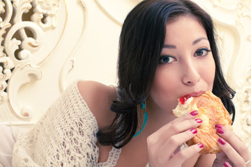 Portrait of young beautiful woman eating her croissant with jam