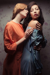 Portrait of two gorgeous girlfriends in blue and orange dresses