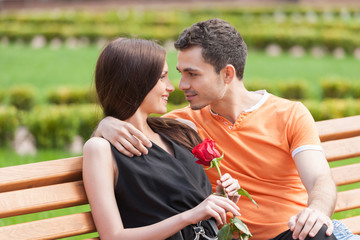 Fototapeta premium Loving couple on the bench. Beautiful young couple sitting close