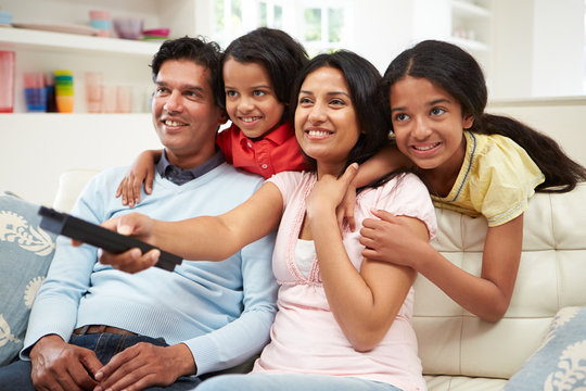 Indian Family Sitting On Sofa Watching TV Together